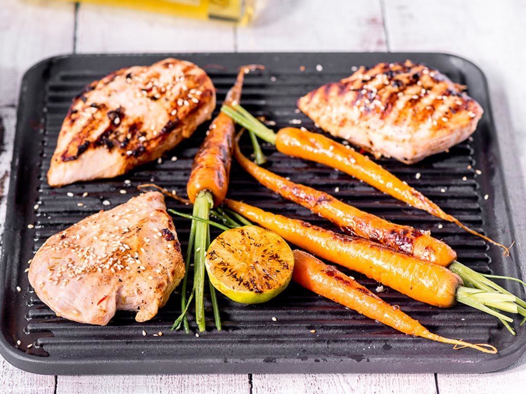 Grillattuja inkivääri-seesambroilereita tarjottimella grillattujen porkkanoiden ja sitruunan kanssa