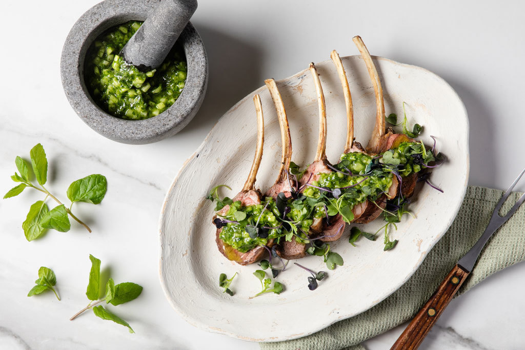 Tuoreista yrteistä valmistettua salsa verdeä karitsanlihan päällä ja morttelissa