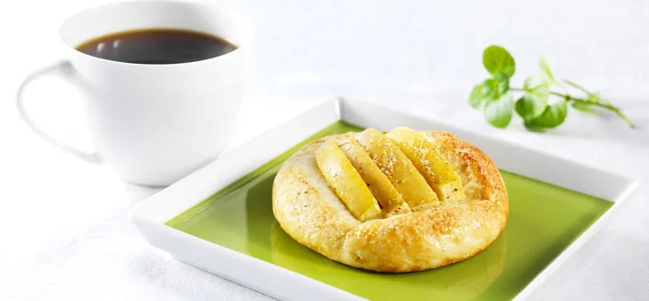 Kuohkea omenapulla vihreällä lautasella ja musta kahvi valkoisessa kahvikupissa